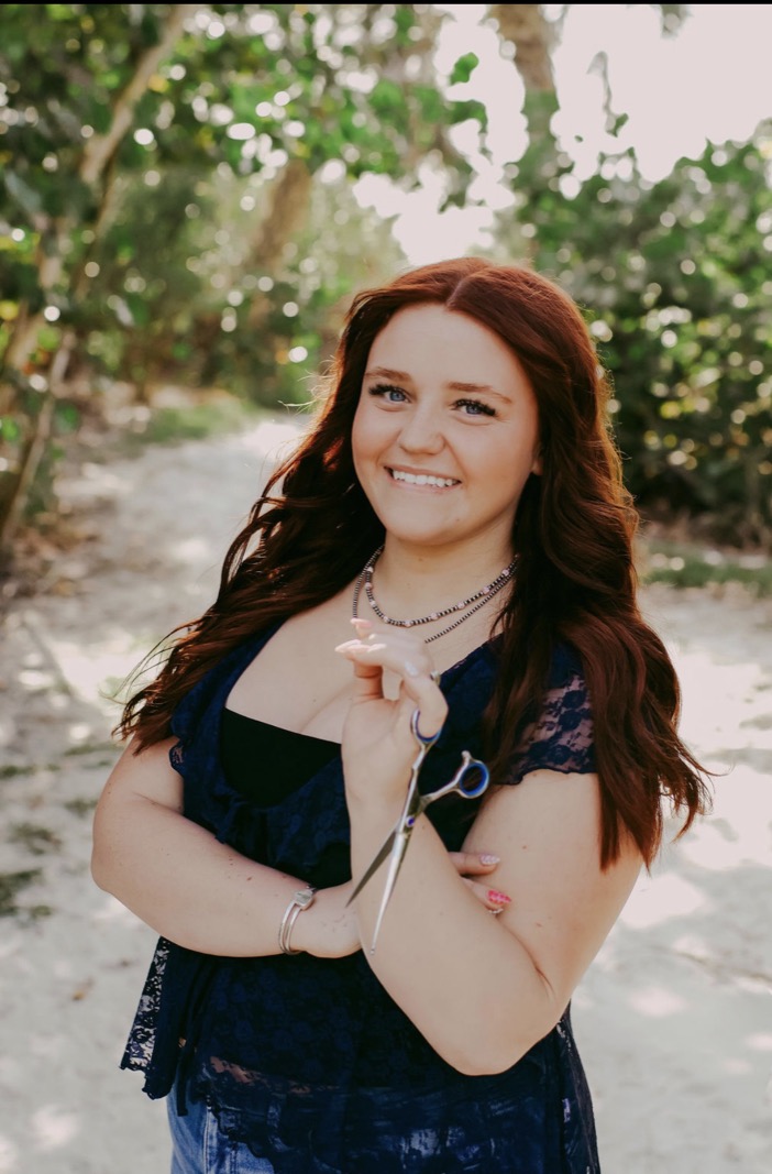 Kenadee Robinson, owner and stylist at Aura Salon, holding styling scissors